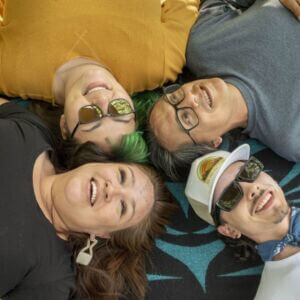 Four people lying down with their head together forming a circle