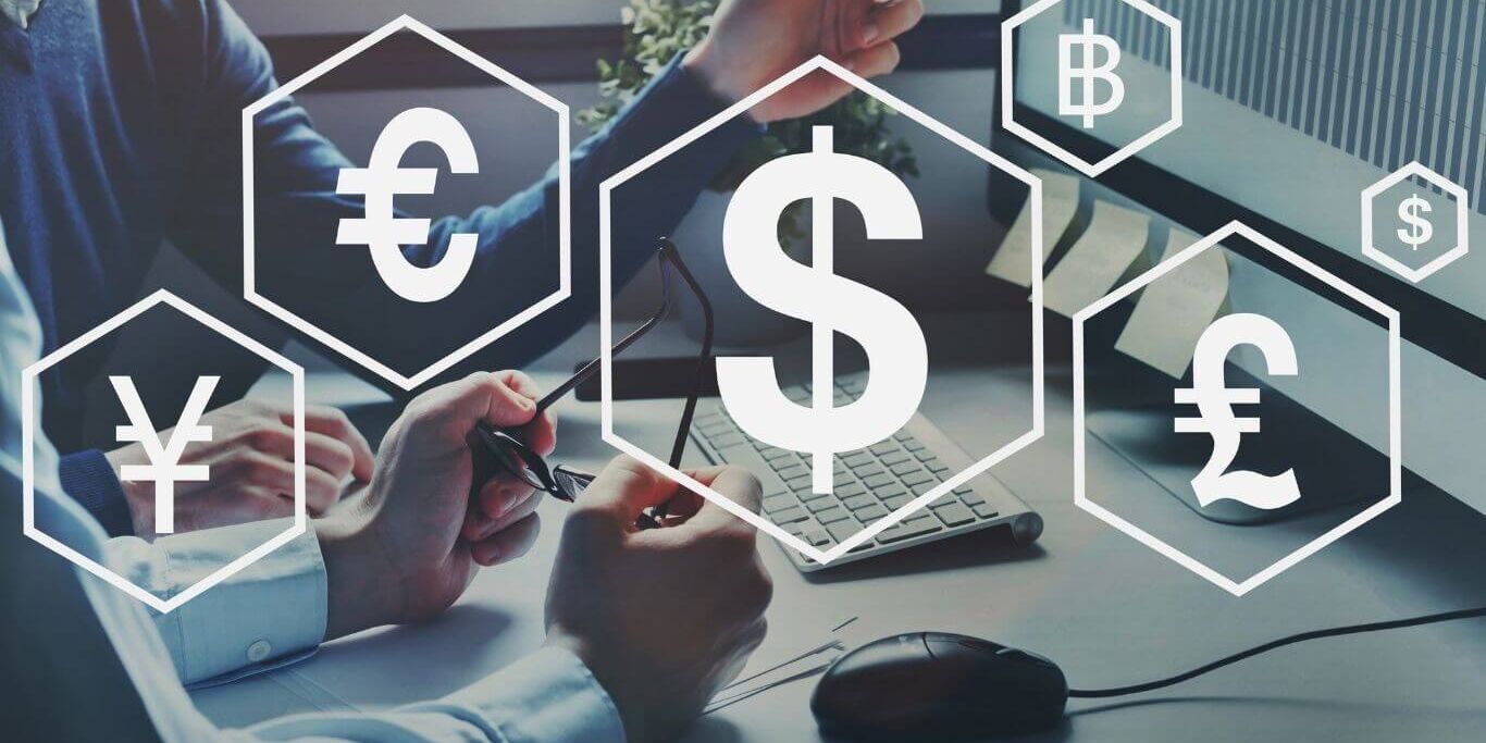 Foreign-direct-investment currency symbols over a photo of a desk with computer.