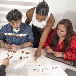 people gathered at meeting table and reviewing various charts and data